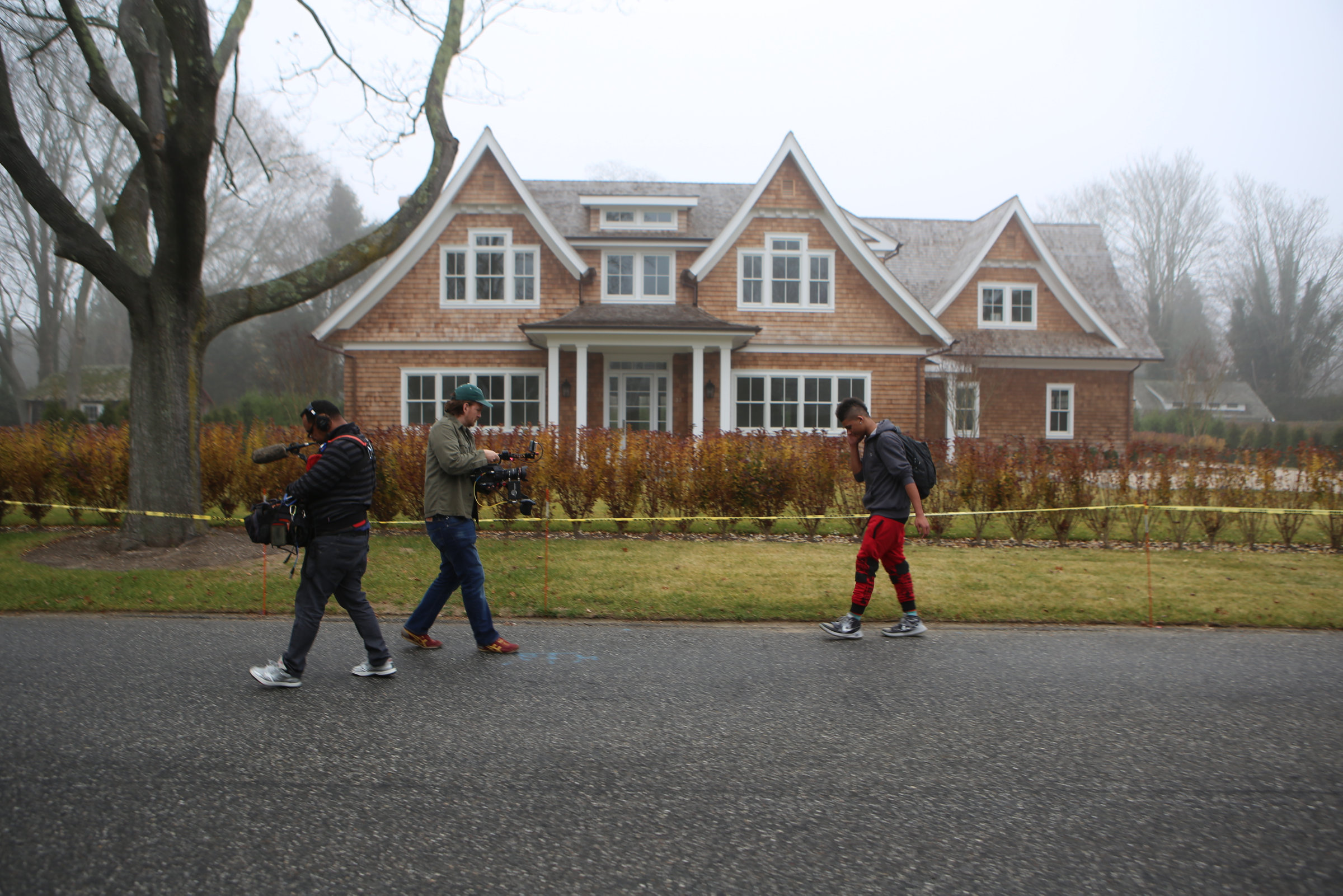 The documentary film crew follows JP Harding as he walks by a house in Bridgehampton.